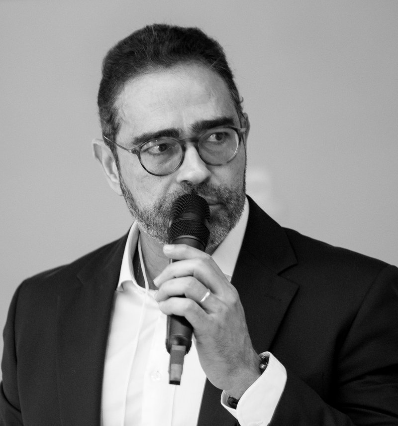 Gustavo Barbosa Vargas falando ao microfone em um painel